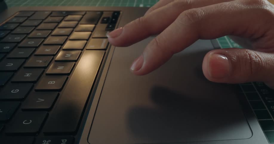 Close-up of a person's fingers tapping and scrolling on the trackpad of a modern laptop