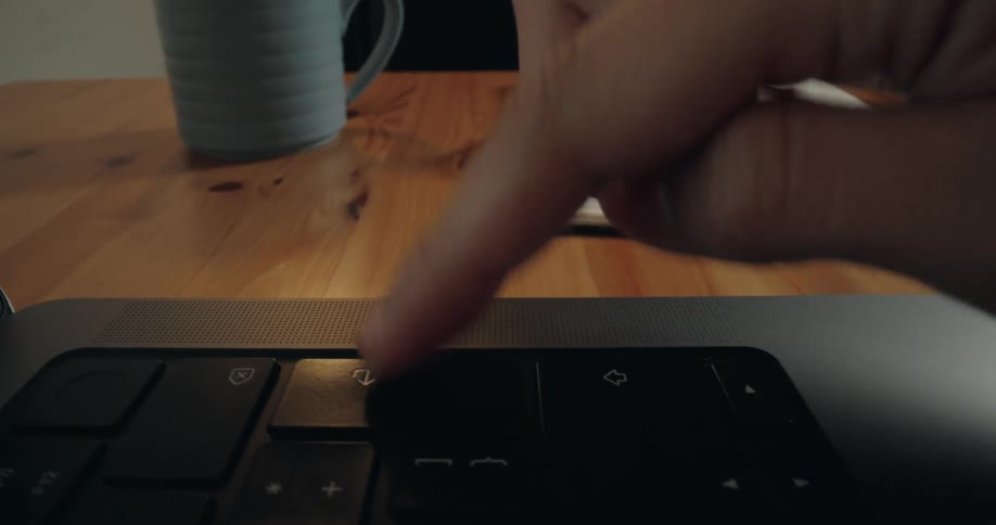 A dramatic push-in shot reveals a finger repeatedly pressing the enter key on a modern laptop keyboard