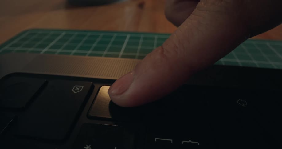 A close-up view of a finger pressing the enter key on a laptop keyboard
