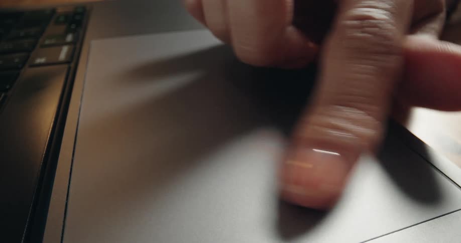 An extreme close-up of a person's finger scrolling and clicking on a laptop trackpad