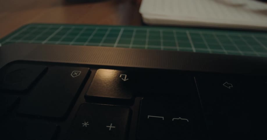 A dynamic macro shot zooms over a laptop keyboard, ending with a finger pressing the Enter key