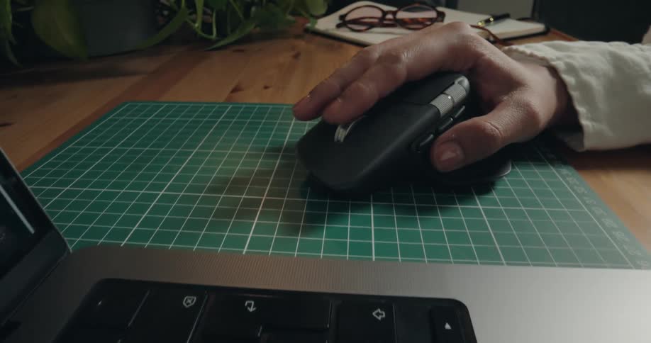 A close-up dolly shot reveals a hand using a wireless mouse to scroll through an e-commerce website on a laptop