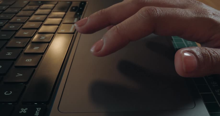 A macro view of fingers tapping, scrolling, and gesturing on the trackpad of a sleek, modern laptop