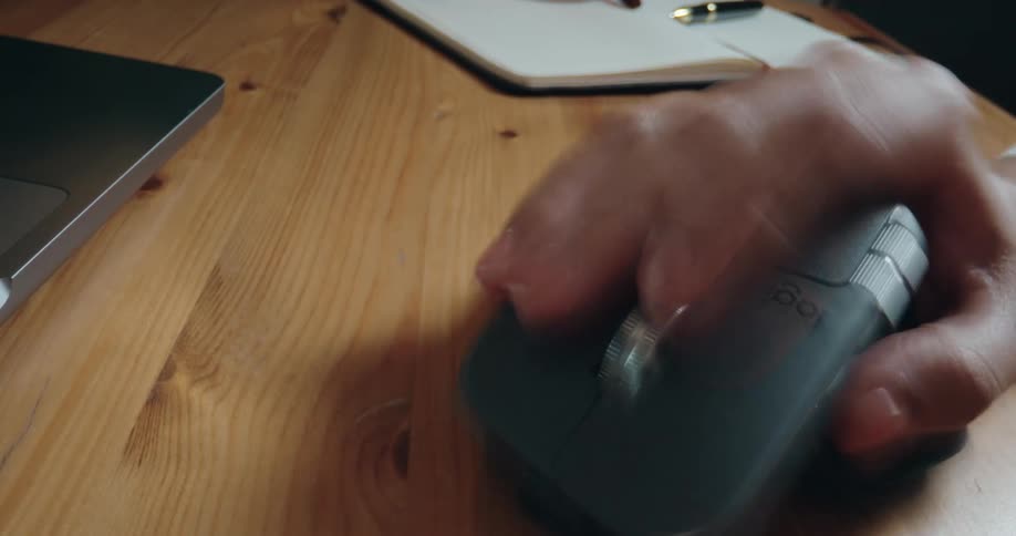 A time-lapse close-up of a hand quickly using a wireless computer mouse on a wooden desk