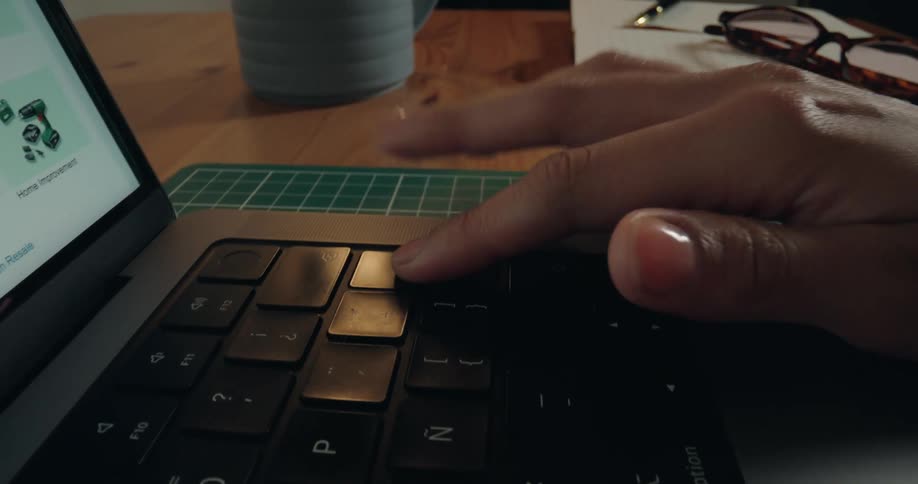 A dynamic close-up shot pushes in on a person's hand repeatedly tapping a key on a laptop keyboard in a modern workspace