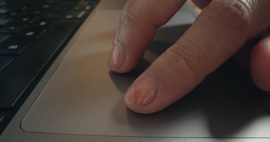 A close-up of fingers tapping and swiping on a modern laptop's grey trackpad