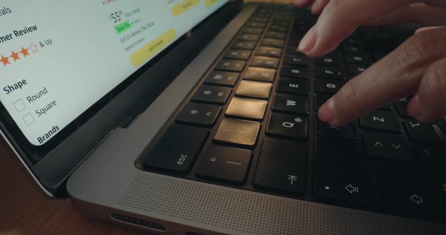 A close-up shot of a person's hands typing on a laptop before pressing the escape key to cancel their online purchase