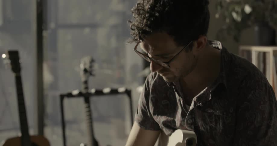 A man strums guitar then stops and thinks