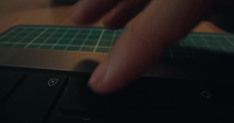 An extreme close-up shot of a finger frantically pressing the down arrow key on a modern laptop