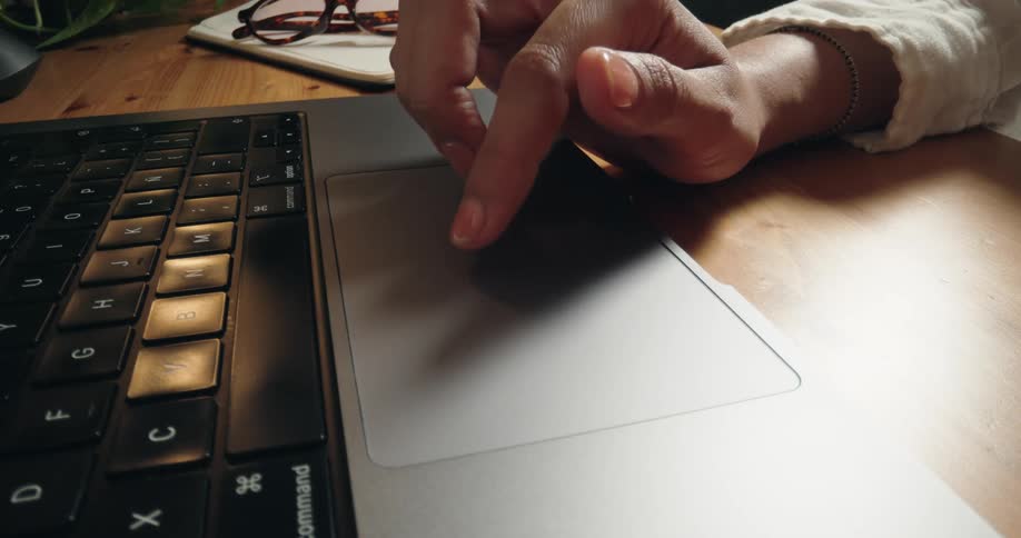 Close-up of a person's hand scrolling and navigating on a modern laptop trackpad
