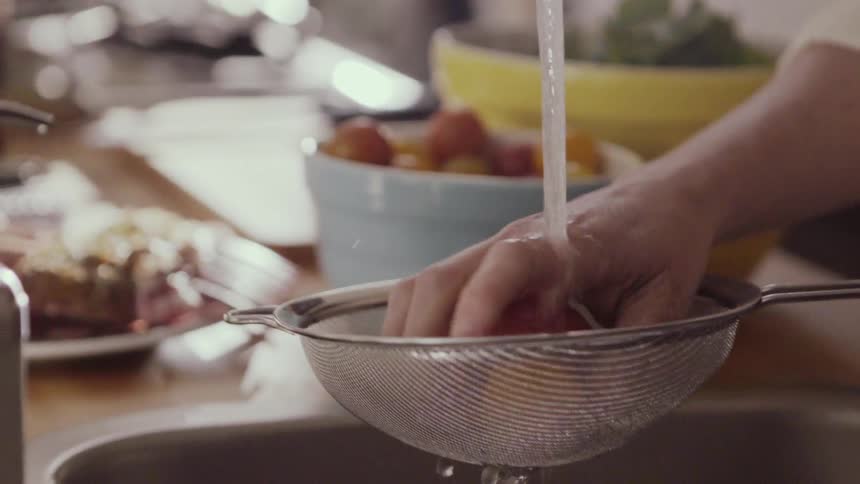 A person cleans some fruit in a sink