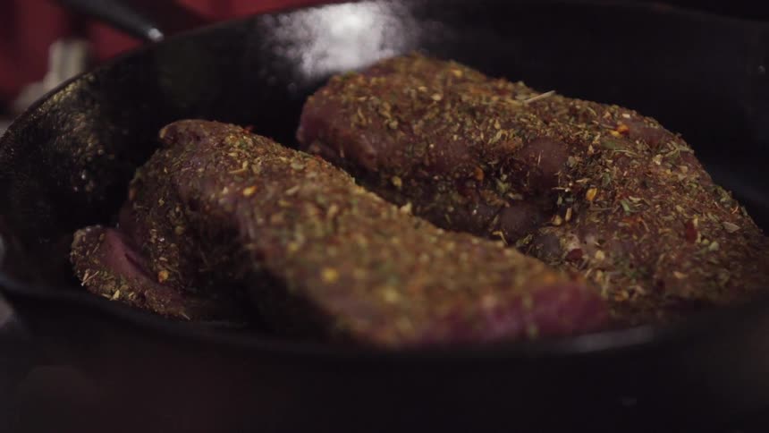 Meat is being seared in a frying pan