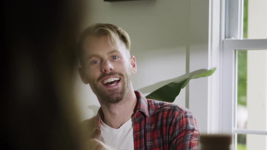 A man in a plaid shirt smiles and talks