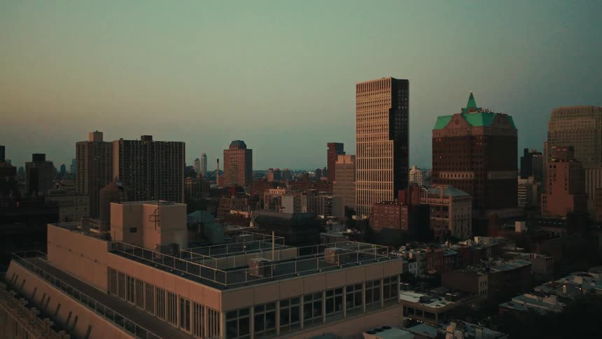 A slow and steady aerial shot moving across the Brooklyn, New York cityscape at sunset
