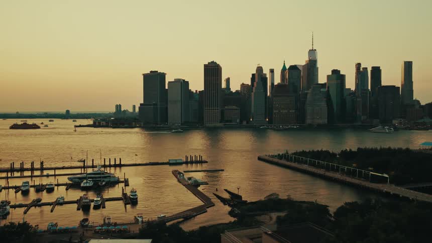An aerial view from Brooklyn reveals the iconic Lower Manhattan skyline and a marina on the East River at golden hour