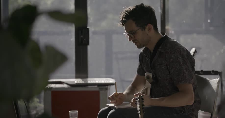 A man is composing a song on the guitar