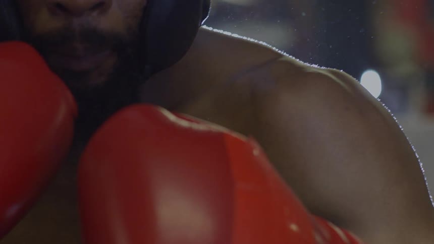 Intense close-up of a boxer in a defensive stance with bright backlighting in slow motion