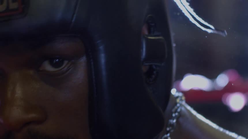 A slow motion close up pans from a red boxing glove to reveal the intense stare of a determined fighter