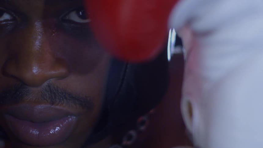 Extreme close-up reveals the intense focus of a boxer wearing headgear as he prepares for a fight