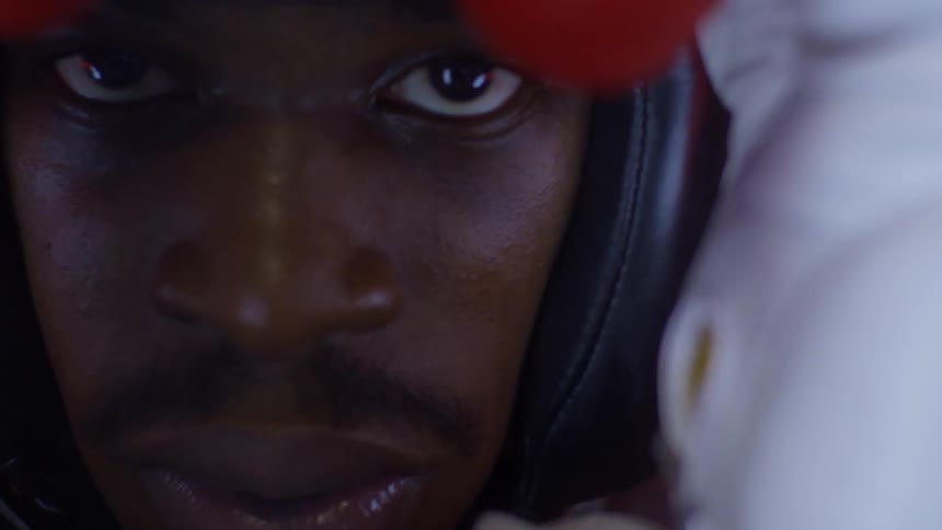 A determined boxer stares intensely into the camera in a dramatic close-up shot