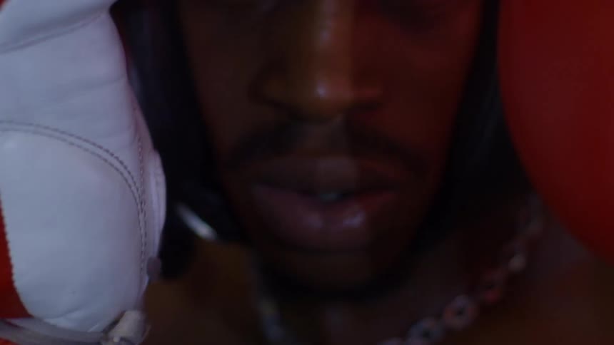 An intense and dramatic close-up of a focused boxer in headgear and red gloves, breathing and staring intensely