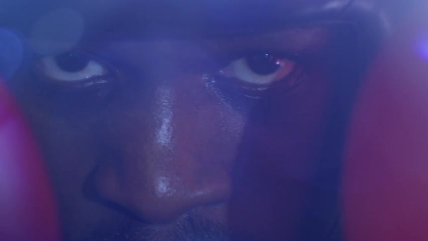 An extreme close-up on the intense and determined eyes of a male boxer, framed by his red boxing gloves