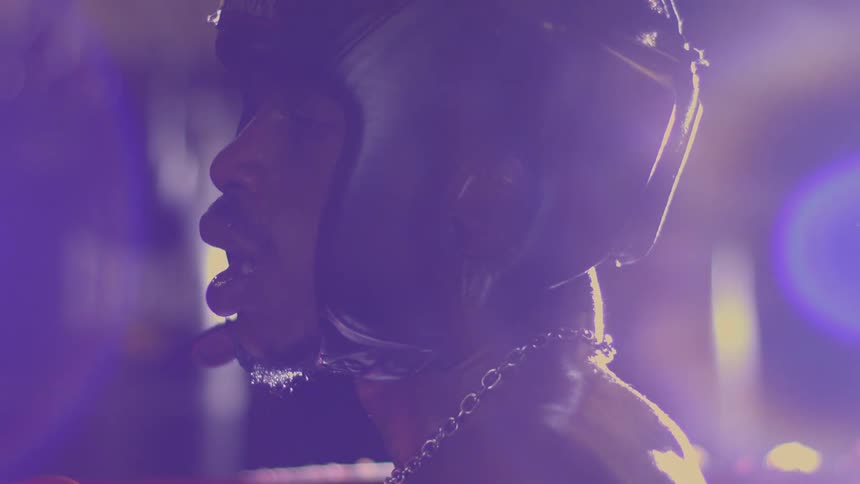 An intense slow motion close-up of a sweaty and exhausted boxer in headgear catching his breath under dramatic purple light