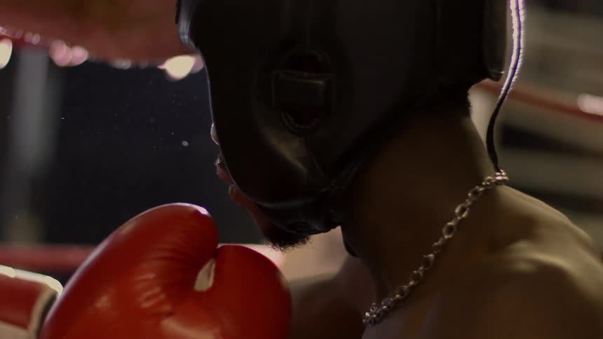 Dramatic slow-motion close-up of a boxer's face as he's punched in the head by his opponent in the ring