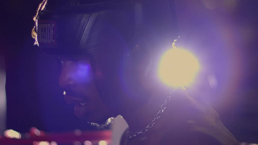 Intense profile of a boxer in headgear, backlit by a strong light in a dark gym