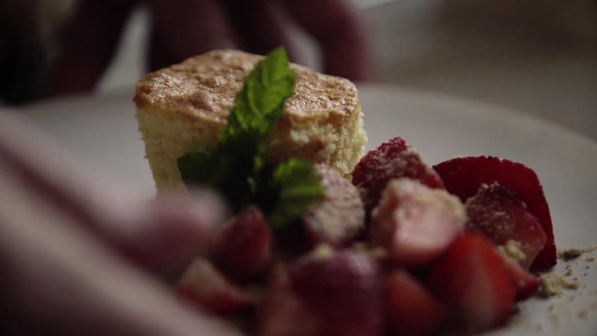 A person sets a desert on a plate and lifts it