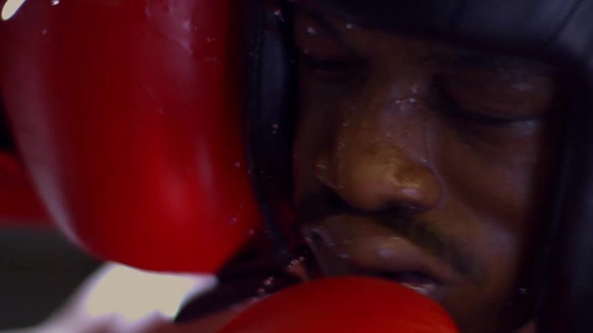 An extreme slow-motion close-up of a boxer getting punched in the face, with sweat flying from the impact