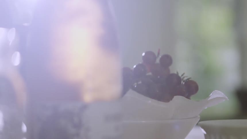 A bottle of liquor next to some grapes