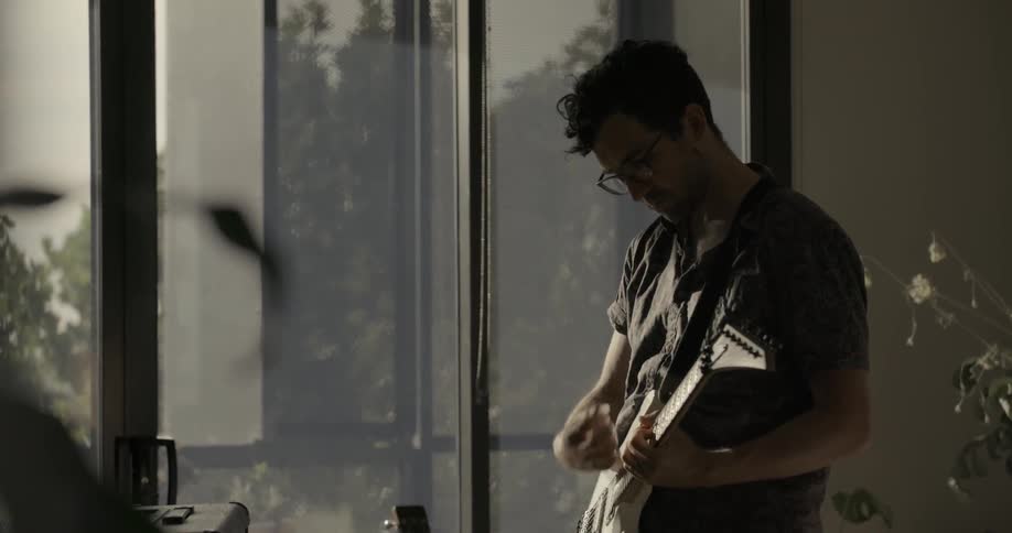 A man playing guitar at home during the day