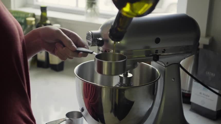 A woman is measuring oil into a measuring cup