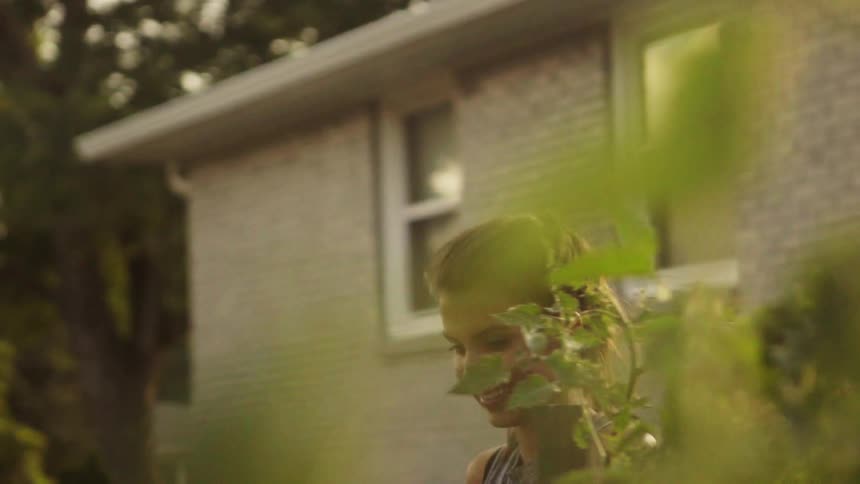 A woman walks past a house into a garden