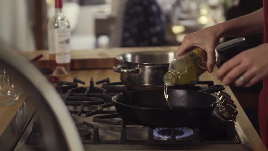 A woman pours oil on a pan