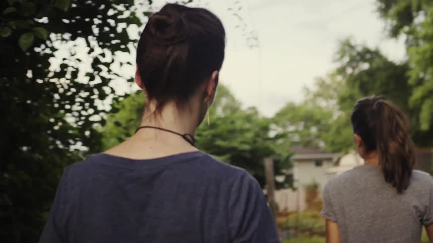 Two women are walking into a backyard garden