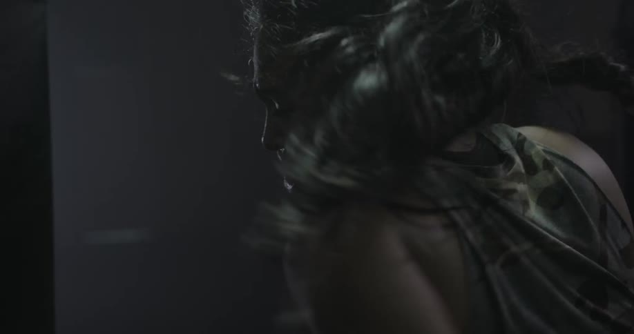 A woman punches furiously in a dark gym