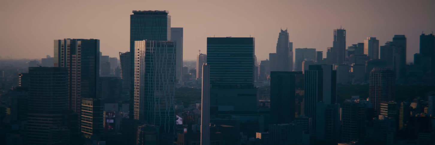 A hazy sunrise casts a warm glow over the still and quiet modern skyline of a sprawling metropolis