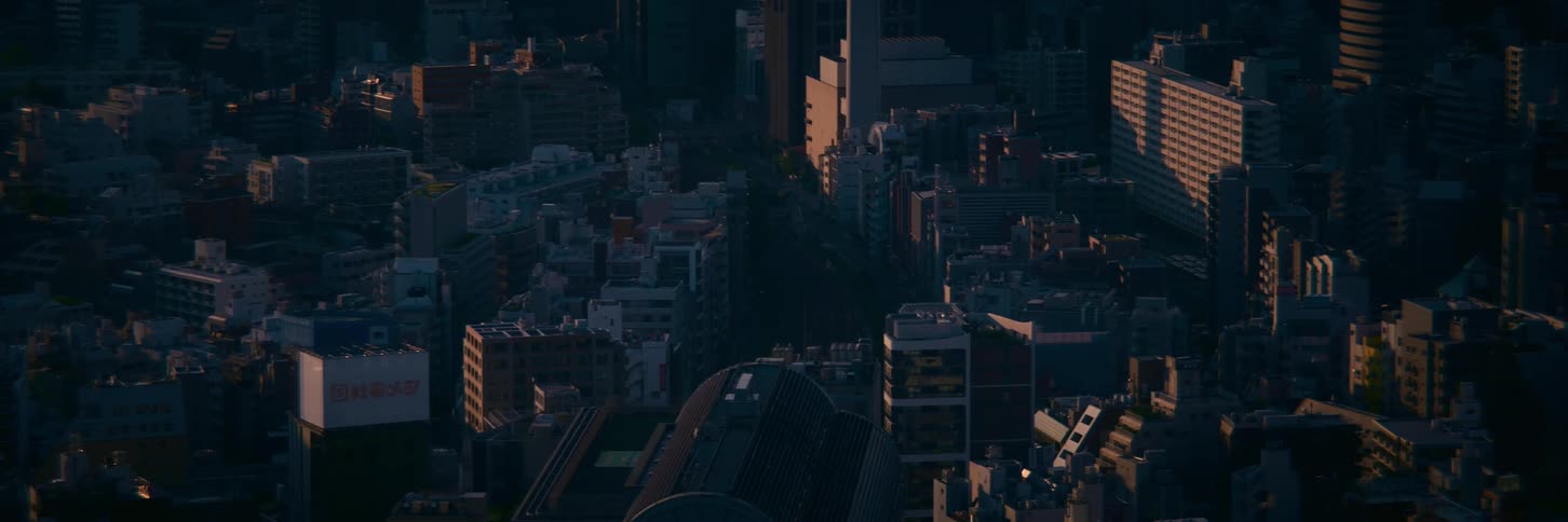 A high-angle static shot of a dense cityscape illuminated by the warm light of sunrise