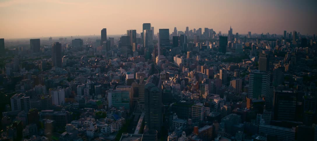 An expansive aerial-style view of a dense urban landscape with skyscrapers silhouetted against a golden sunset