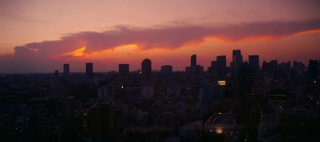A blinking-eye perspective from a high-rise window reveals the Tokyo city skyline under a stunning purple and orange sunset