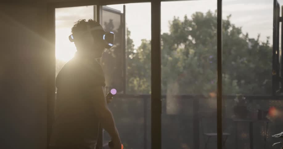 A man swings a controller playing virtual reality