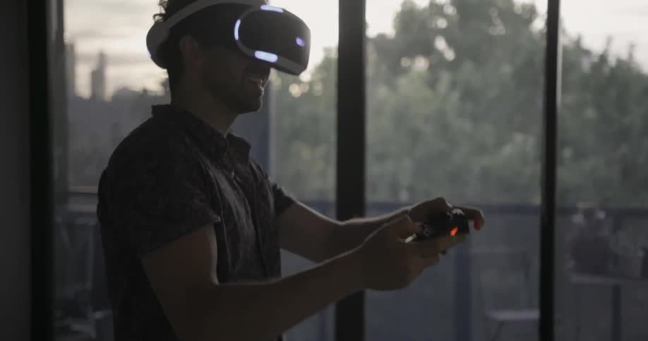 A man is wearing a virtual reality headset while laughing and playing