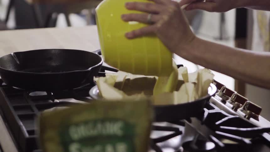 A woman pours batter from a bowl into a cake pan