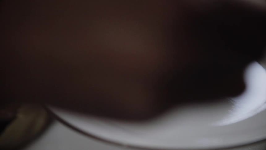 White sauce being scooped onto a white plate with a spoon