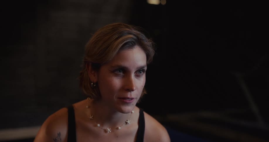 Close-up of an attentive young woman smiling warmly while listening during a conversation in a dimly lit setting