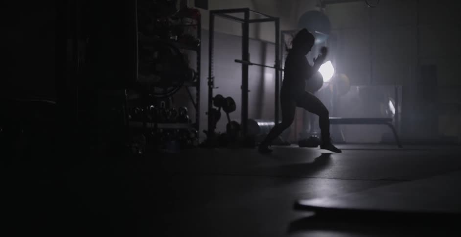 Woman in dark gym practicing boxing