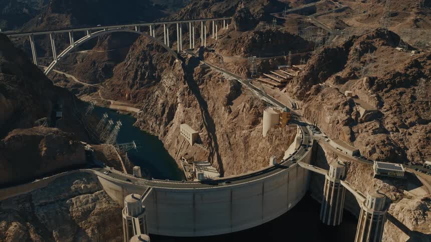 A stunning high-angle view slowly reveals the Hoover Dam and the Mike O'Callaghan–Pat Tillman Memorial Bridge, nestled within the vast, rocky canyon