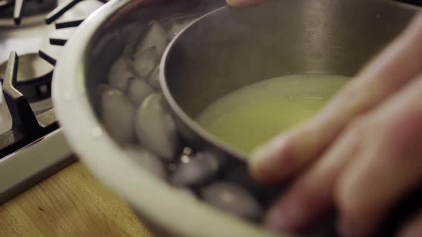 Person puts a bowl of hot liquid into another bowl full of ice
